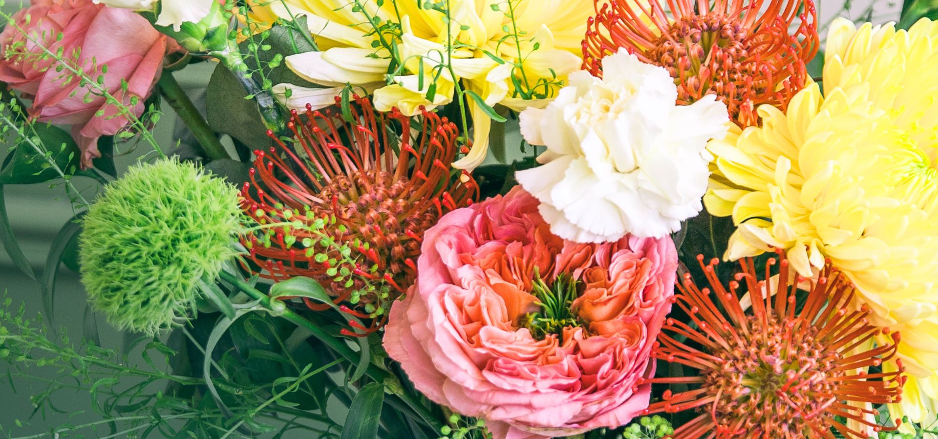 Primer plano panorámico de flores de la Colección de Verano de Colvin con rosas de jardín, crisantemos amarillos y nutans naranjas.