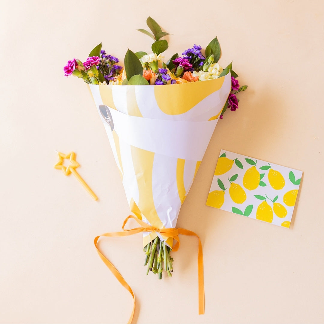 Ramo de flores coloridas con envoltorio, vela y tarjeta