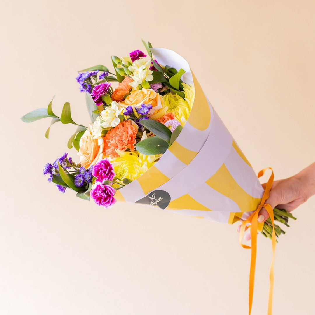 Ramo de flores coloridas con envoltorio, vela y tarjeta