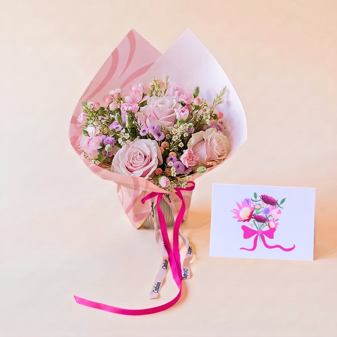 Arreglo de rosas rosas con envoltorio y tarjeta