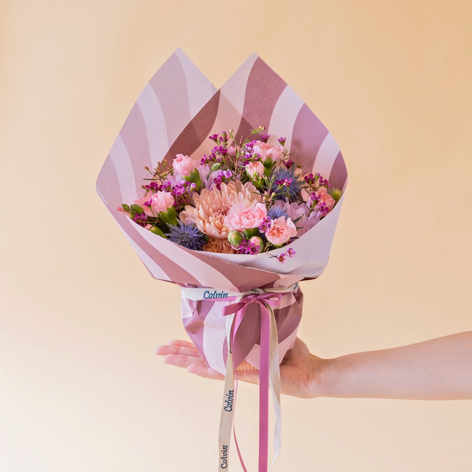 Arranjo de flores roxas com embrulho e cartão