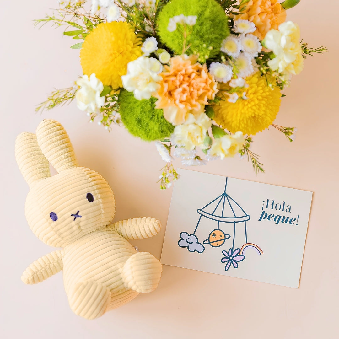 Detalle del pack de arreglo de flores amarillas, cremas y verde con peluche Miffy color amarillo y una tarjeta "¡Hola Peque!"