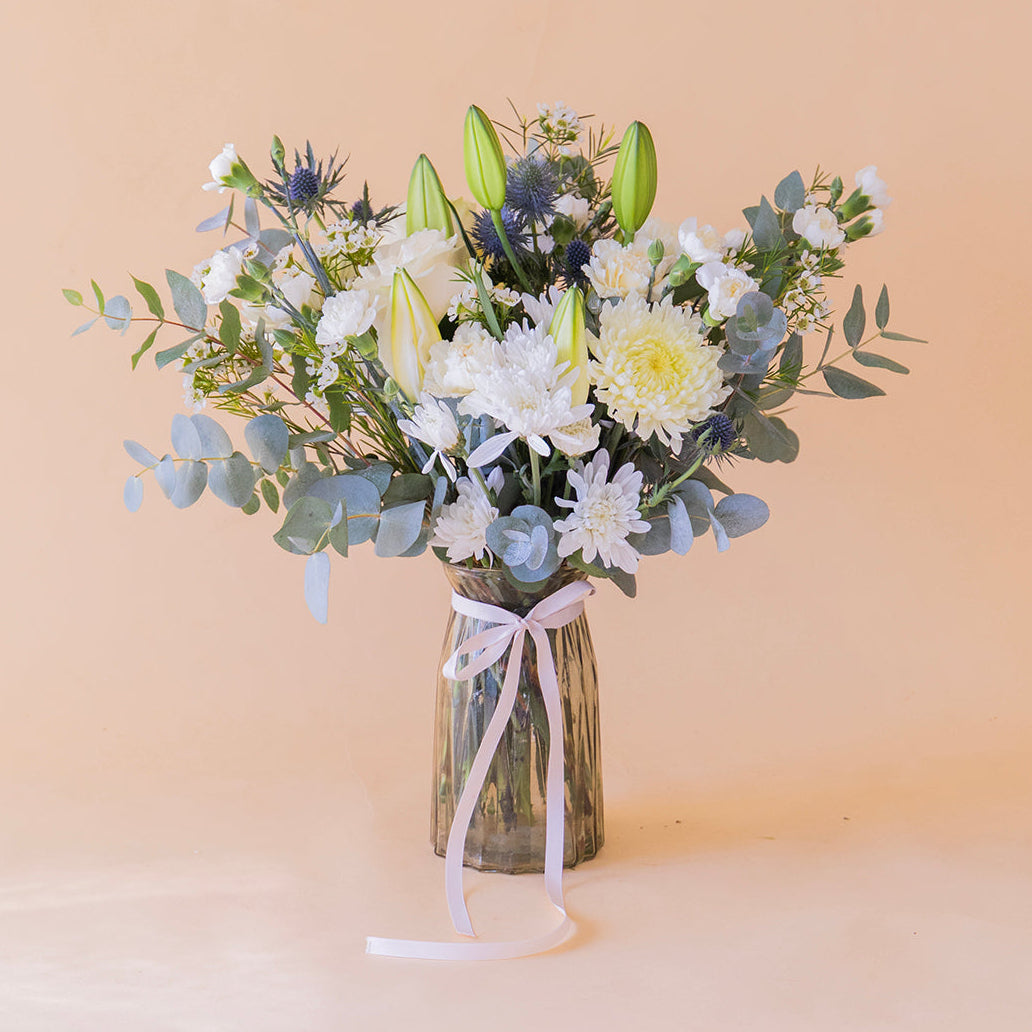 Ramo de flores blancas con lirios sobre fondo crema.