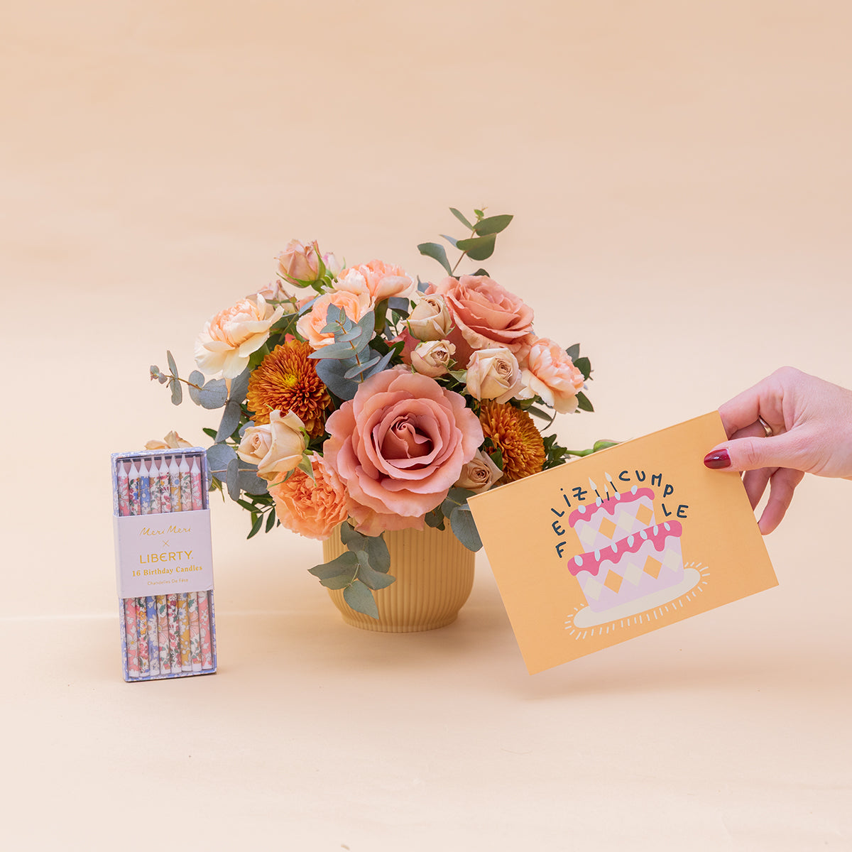 Arranjo floral Liberty com velas e cartão.