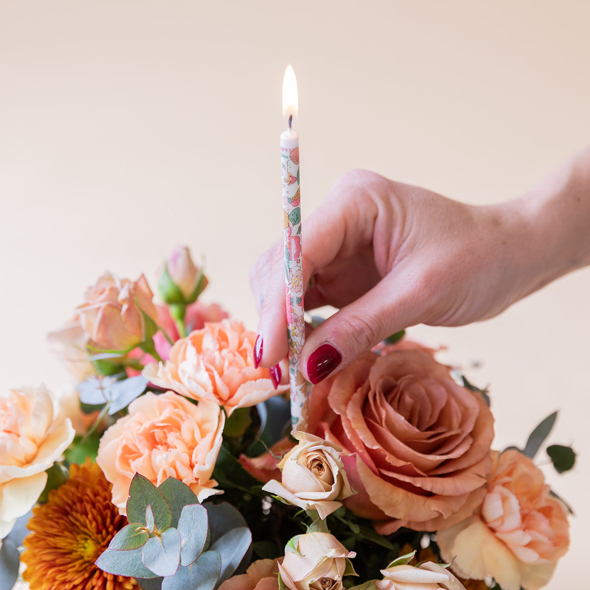 Arranjo floral Liberty com velas e cartão.