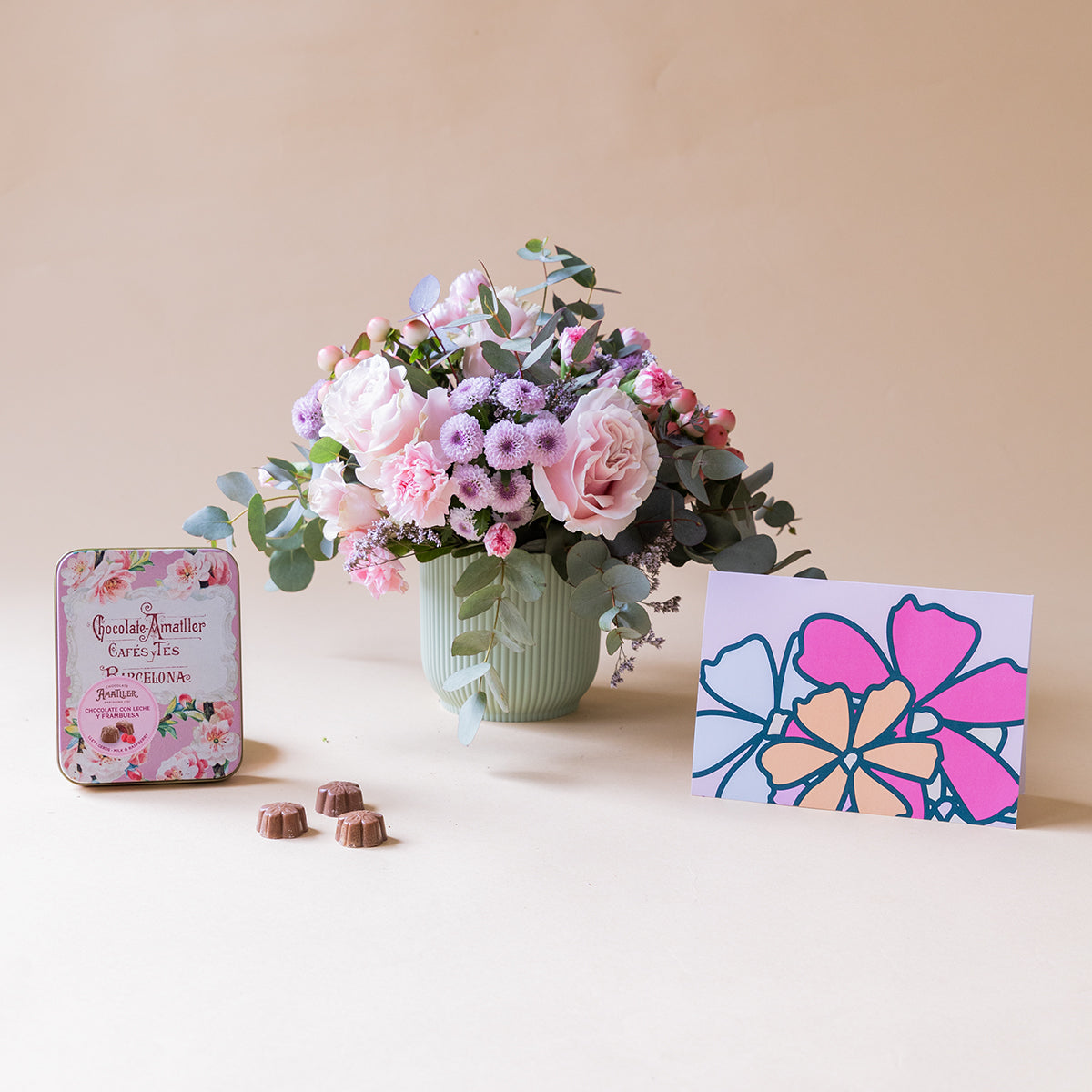 Arranjo de rosas cor-de-rosa com chocolates e cartão.
