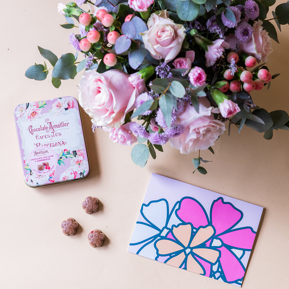 Arranjo de rosas cor-de-rosa com chocolates e cartão.