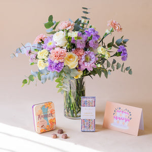 Ramo de flores pastel con velas, bombones y tarjeta