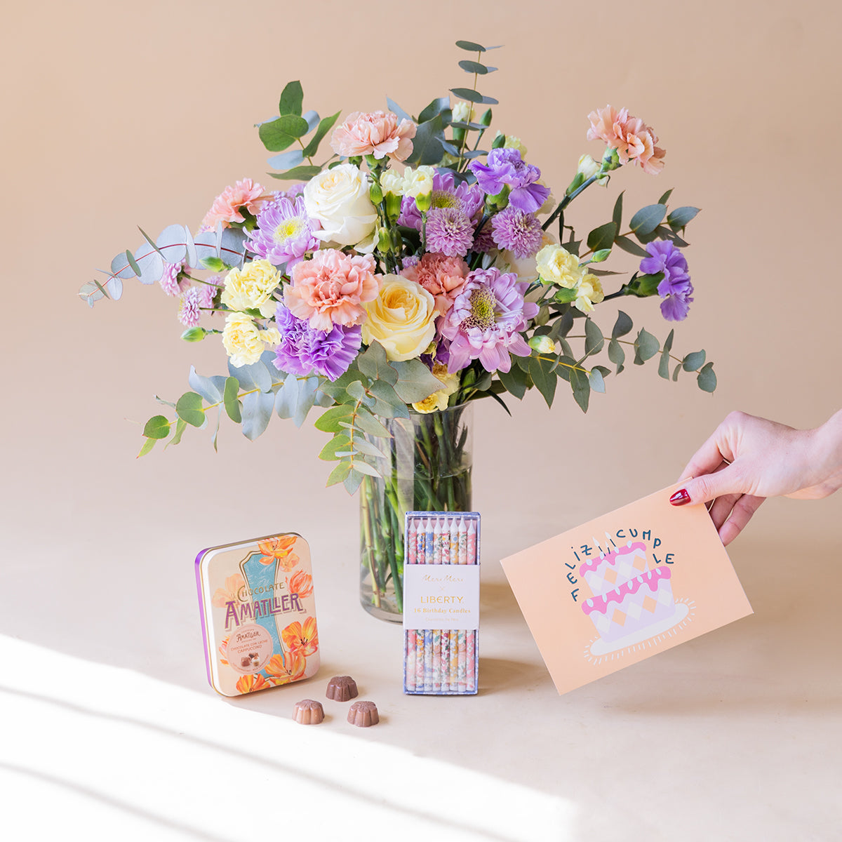 Ramo de flores pastel con velas, bombones y tarjeta