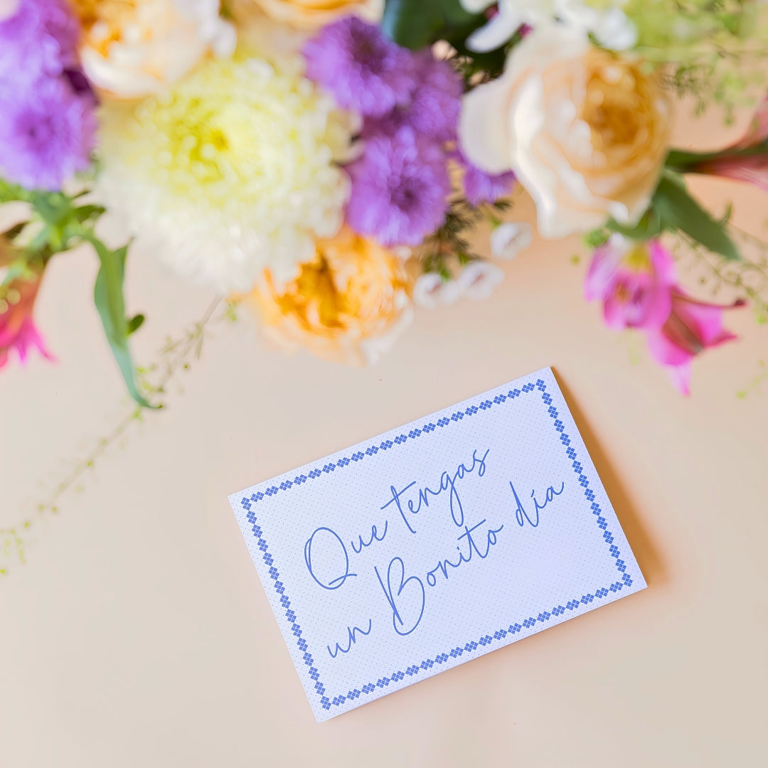 Detalle del pack de Ramo de flores frescas de Colvin, La Costa con rosas de jardín melocotón, alstroemerias y crisantemos, junto a una tarjeta de felicitación con la frase "Que tengas un Bonito día" sobre un fondo liso de color crema.