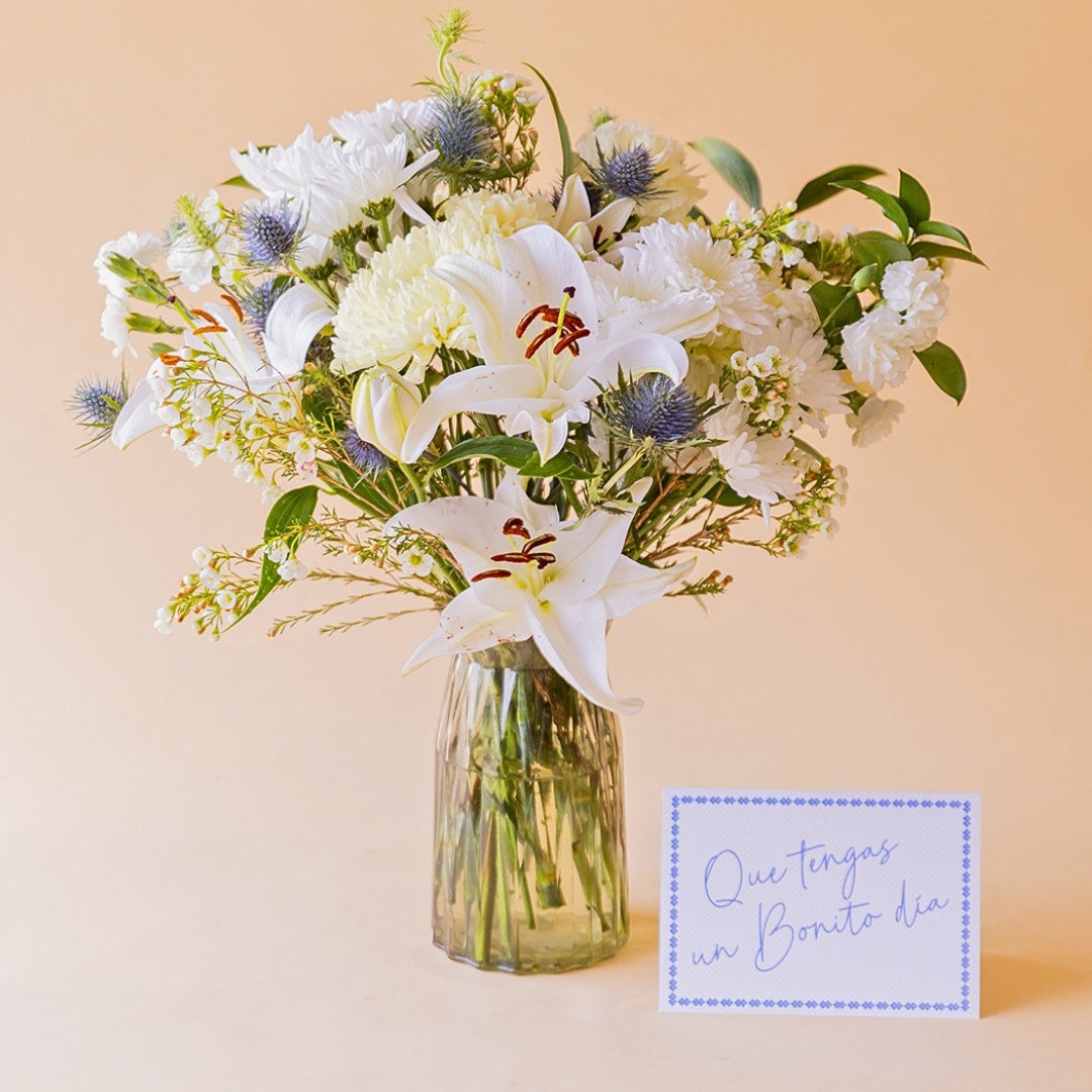 Ramo de flores blancas Colvin con lirio, crisantemo y eryngium en jarrón Gala de cristal, junto a tarjeta "Que tengas un Bonito día"