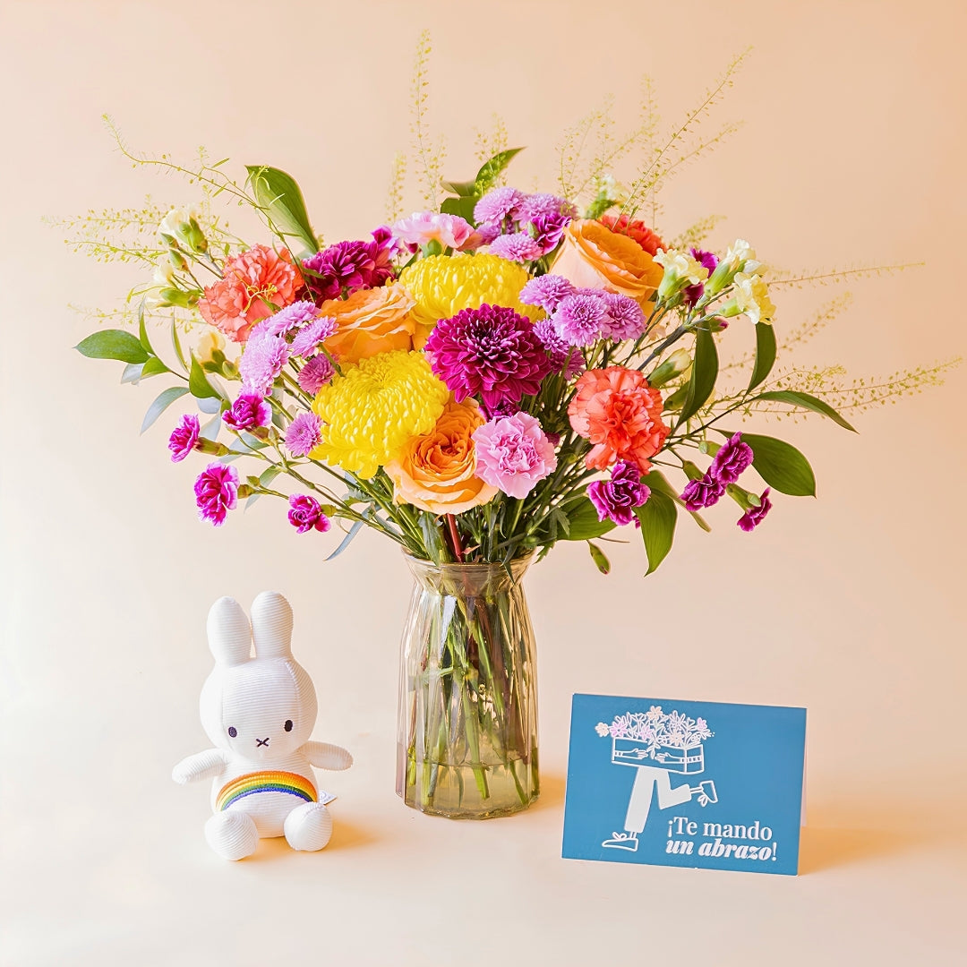 Ramo de flores coloridas de Colvin en jarrón de cristal con peluche Miffy arcoíris y tarjeta azul "¡Te mando un abrazo!"
