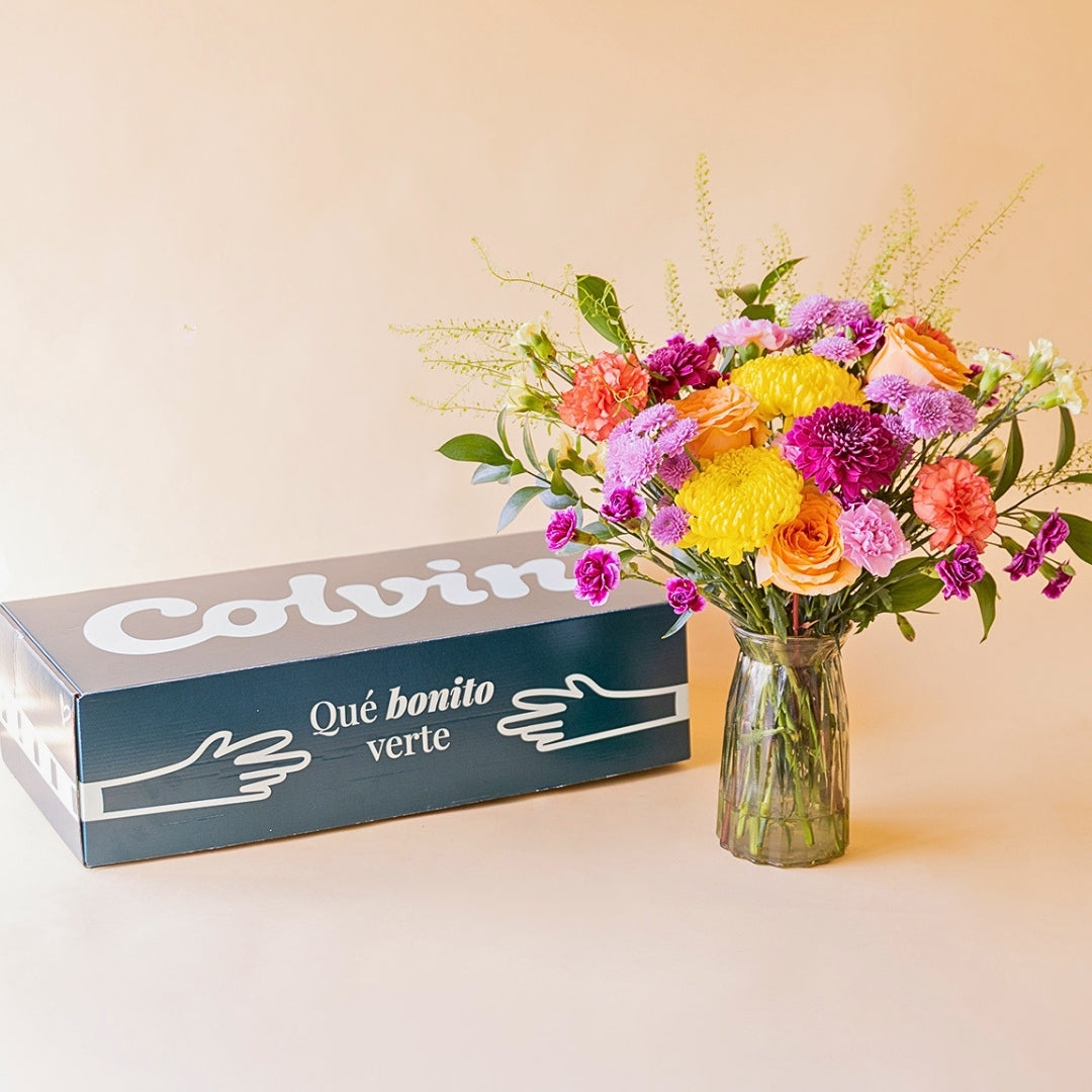 Ramo de flores de cumpleaños en jarrón junto a caja de envío de Colvin con mensaje "Qué bonito verte"