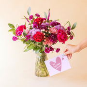 Ramo de flores rojas con jarrón de cristal y tarjeta "Te quiero mucho" de Colvin