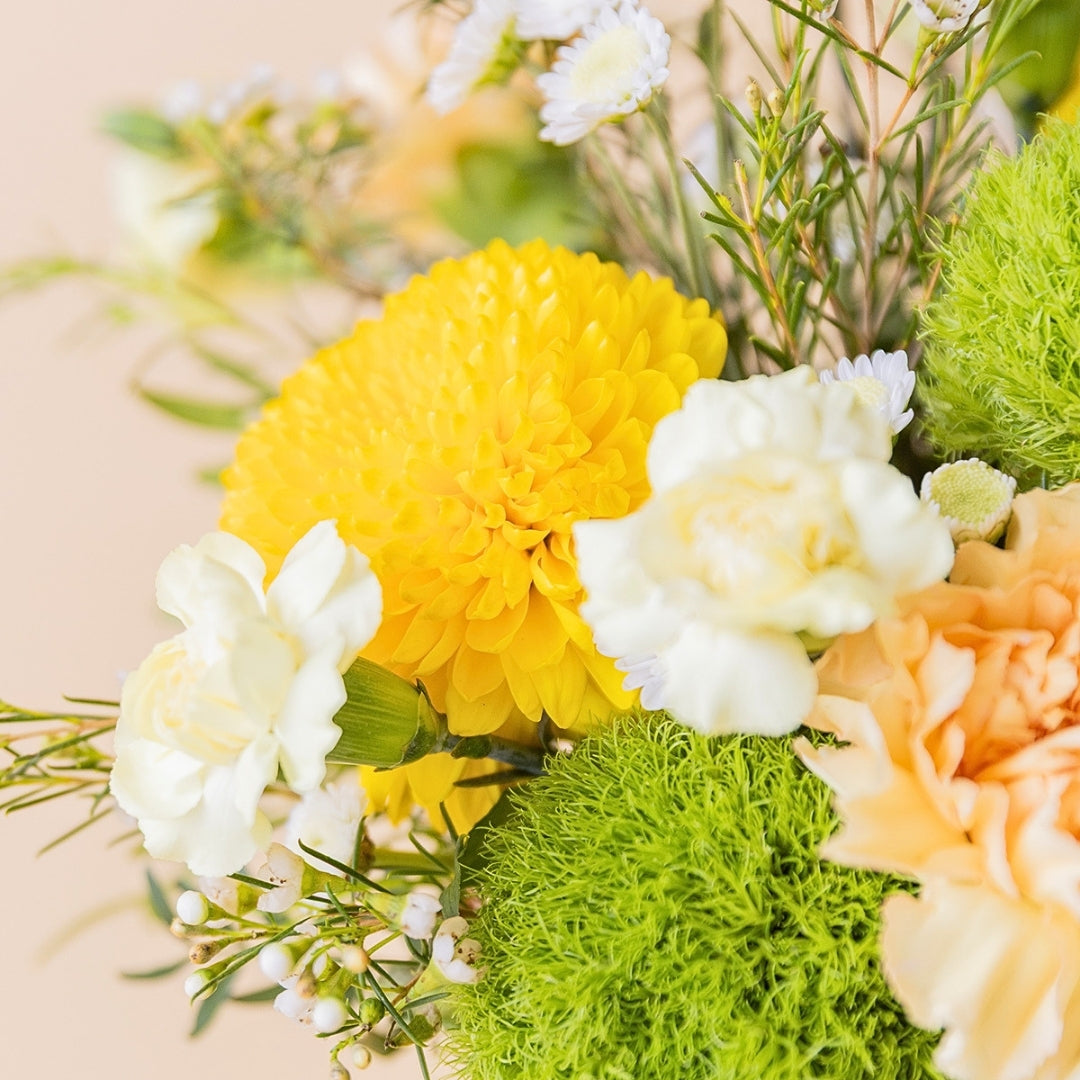 Detalle de cerca del arreglo de verano El Chiringuito de Colvin, destacando crisantemos amarillos, claveles, flores verdes y crema