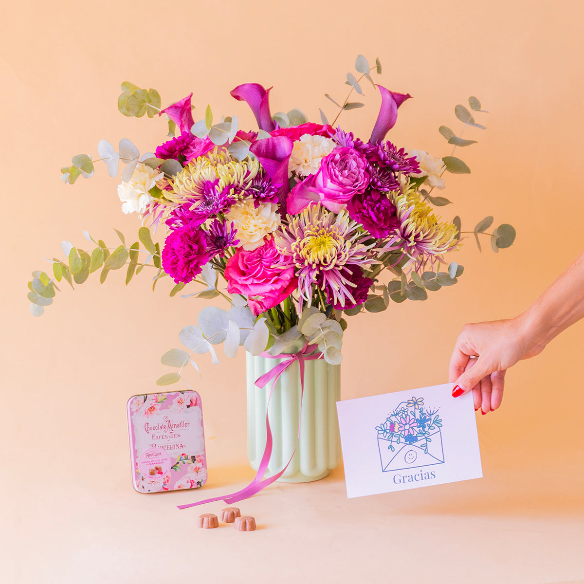 Mano sosteniendo la tarjeta Gracias junto al Ramo Euforia de calas moradas y bombones Amatller frambuesa — Colvin