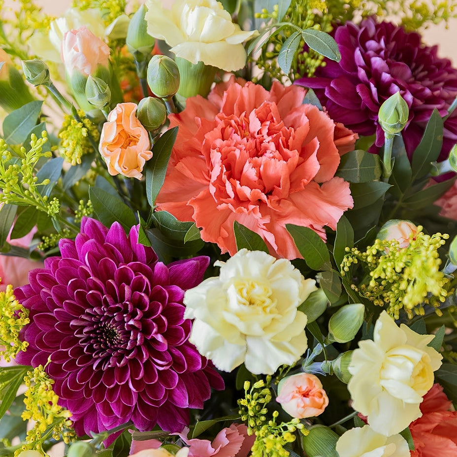 La Chispa - Detalle de arreglo floral con claveles amarillos y naranjas con crisantemos morados de Colvin.