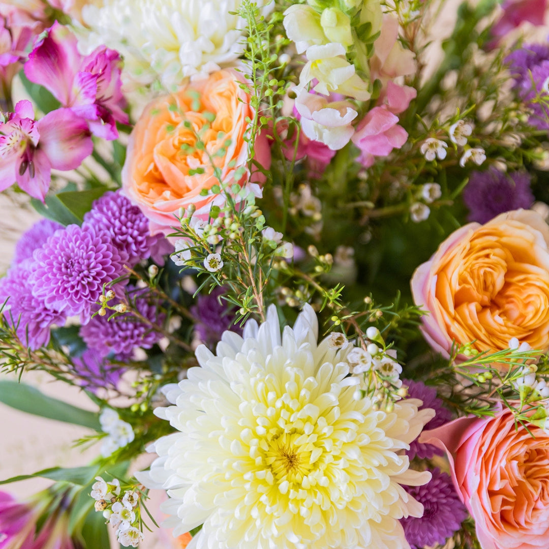Detalle del ramo de flores Costa de Colvin con rosas de jardín melocotón, crisantemos blancos y flores rosa vibrante.