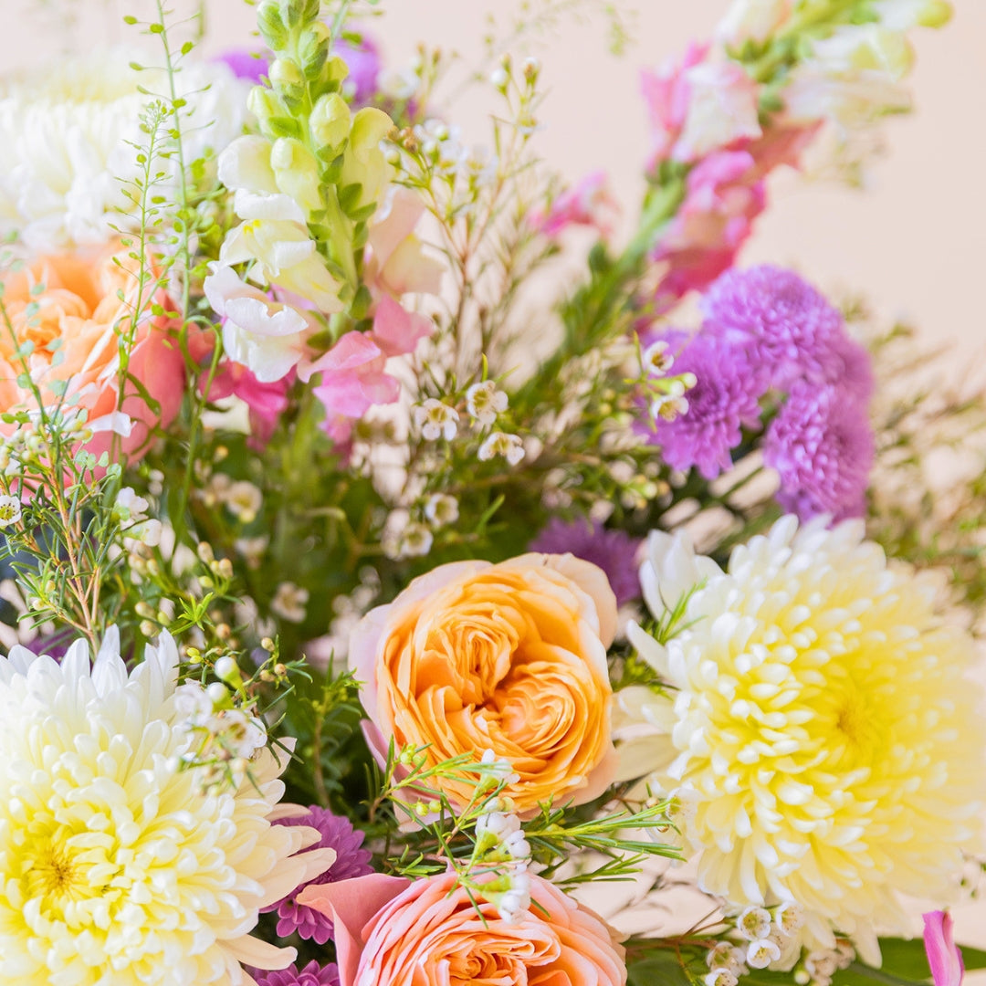 Detalle del ramo de flores Costa de Colvin con rosas de jardín melocotón, crisantemos blancos y flores rosa vibrante.