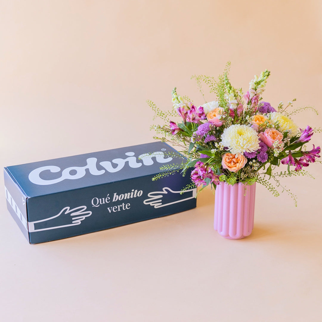 Ramo de flores Costa en un jarrón rosa junto a la caja de regalo de Colvin con el mensaje "Qué bonito verte".