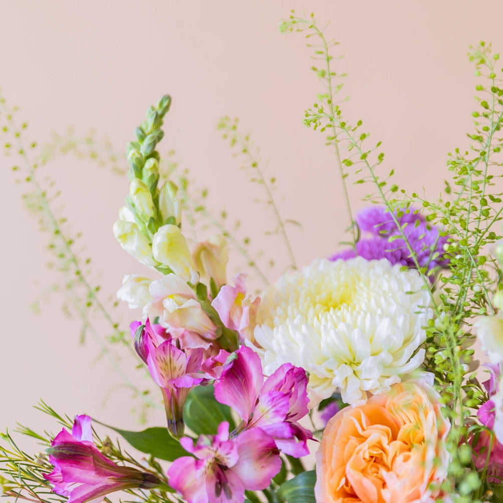 Detalle del ramo de flores Costa de Colvin con rosas de jardín melocotón, crisantemos blancos y flores rosa vibrante.