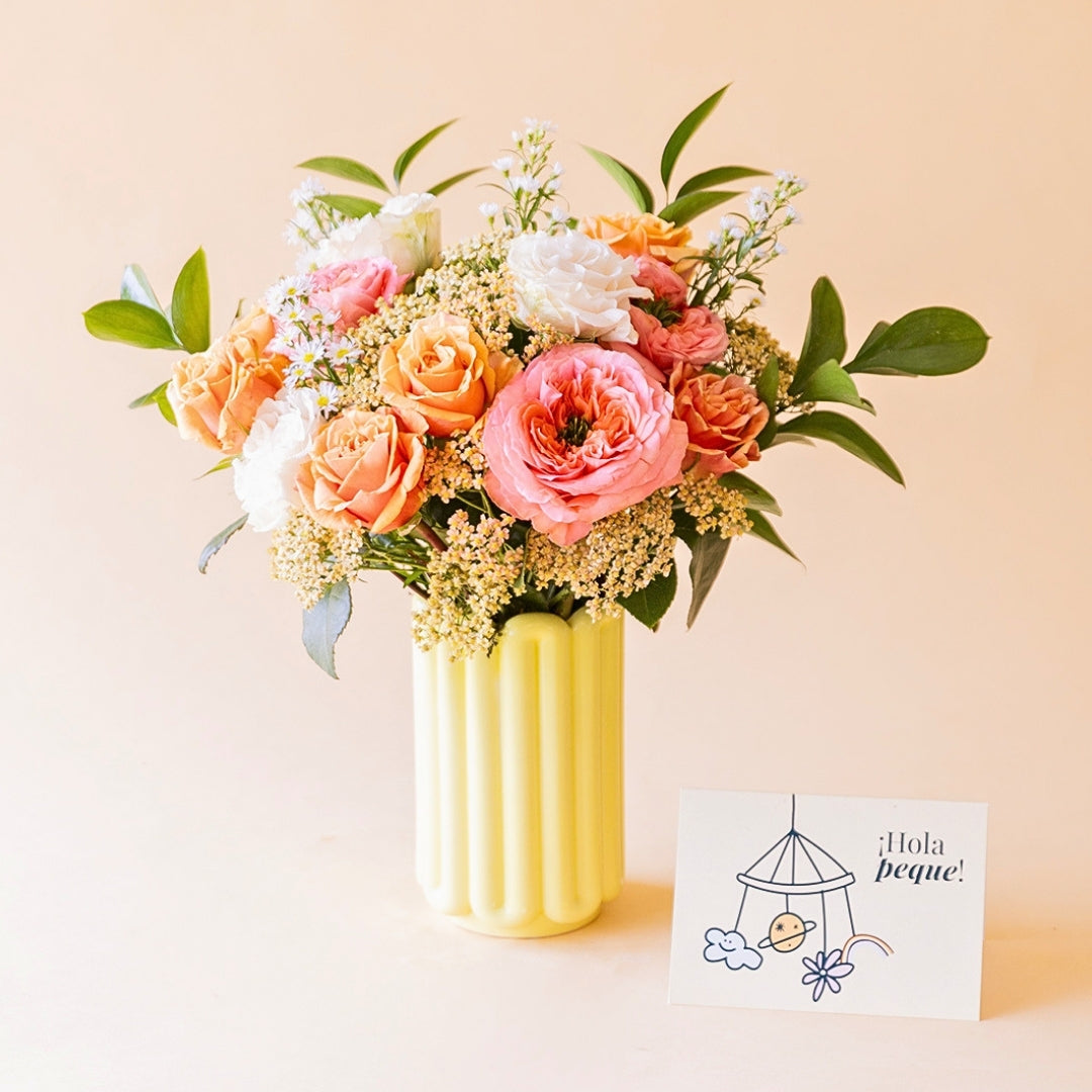 Ramo Colvin de rosas de jardín melocotón, achillea y aster crema en jarrón de cerámica Alba amarillo, junto a tarjeta ¡Hola peque!