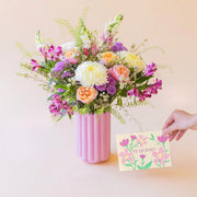 La Costa - Ramo de verano de Colvin en jarrón rosa con mano sosteniendo tarjeta floral "Te Quiero".