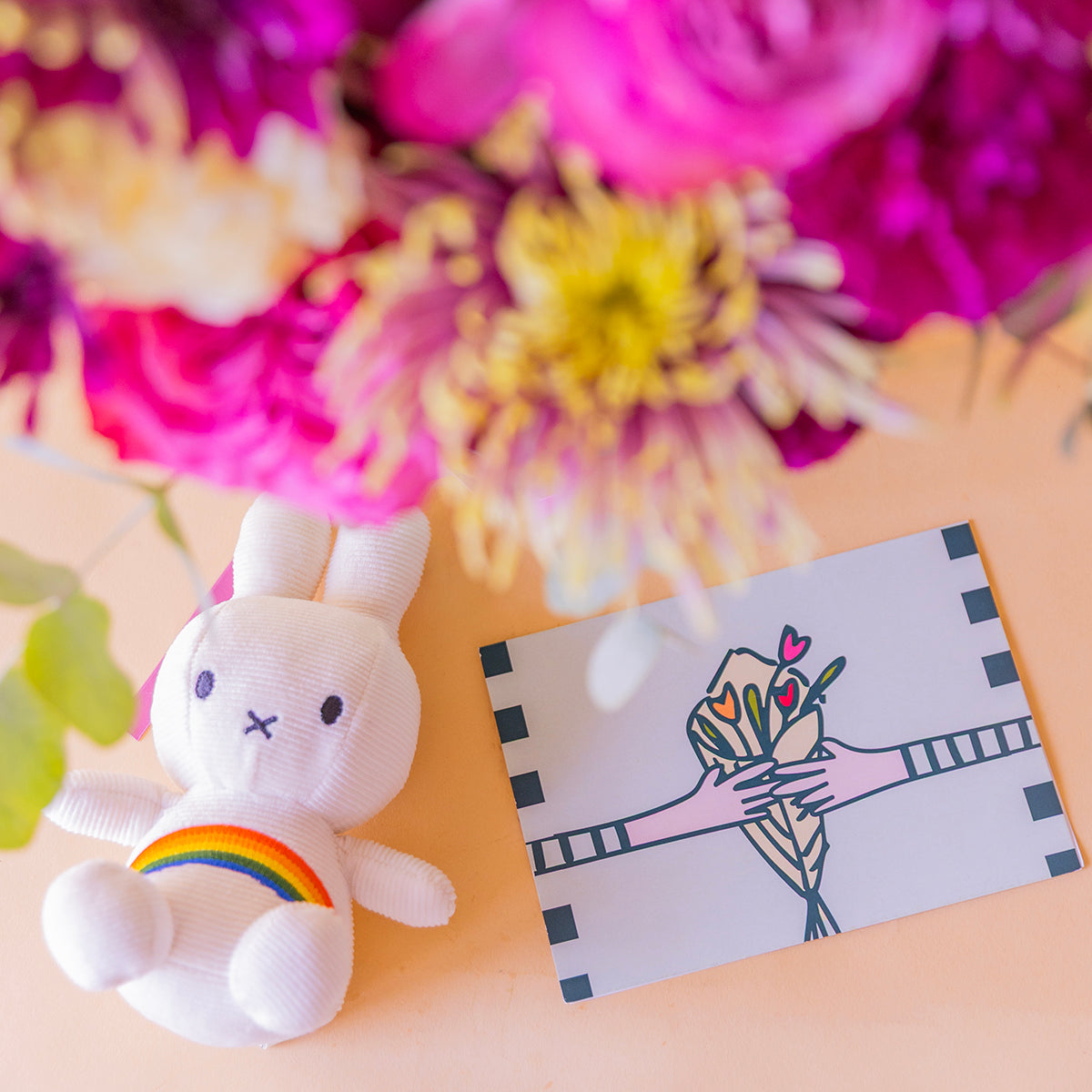 Detalle de peluche Miffy arcoíris y tarjeta Más que Flores con rosas garden y crisantemos al fondo — Colvin