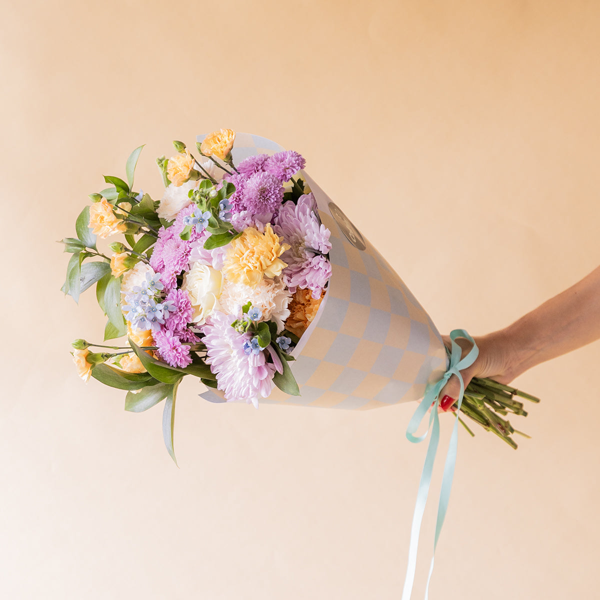 Ramo de flores pastel con crisantemos lilas, claveles melocotón y no me olvides azules, envoltorio cuadros - Colvin
