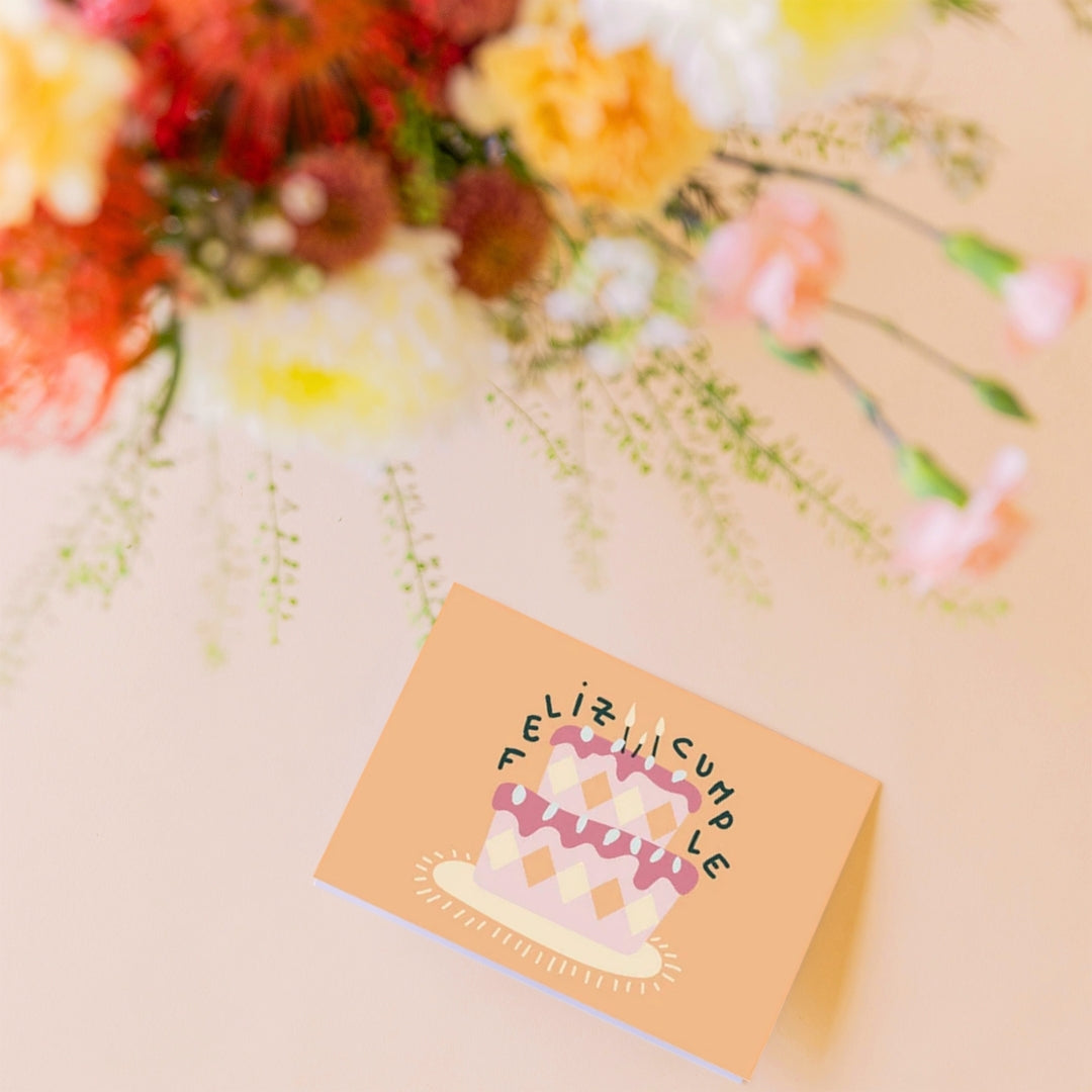Detalle del ramo de flores de verano de Colvin, La Jarana  con una tarjeta de felicitación de Feliz Cumpleaños sobre un fondo color crema.