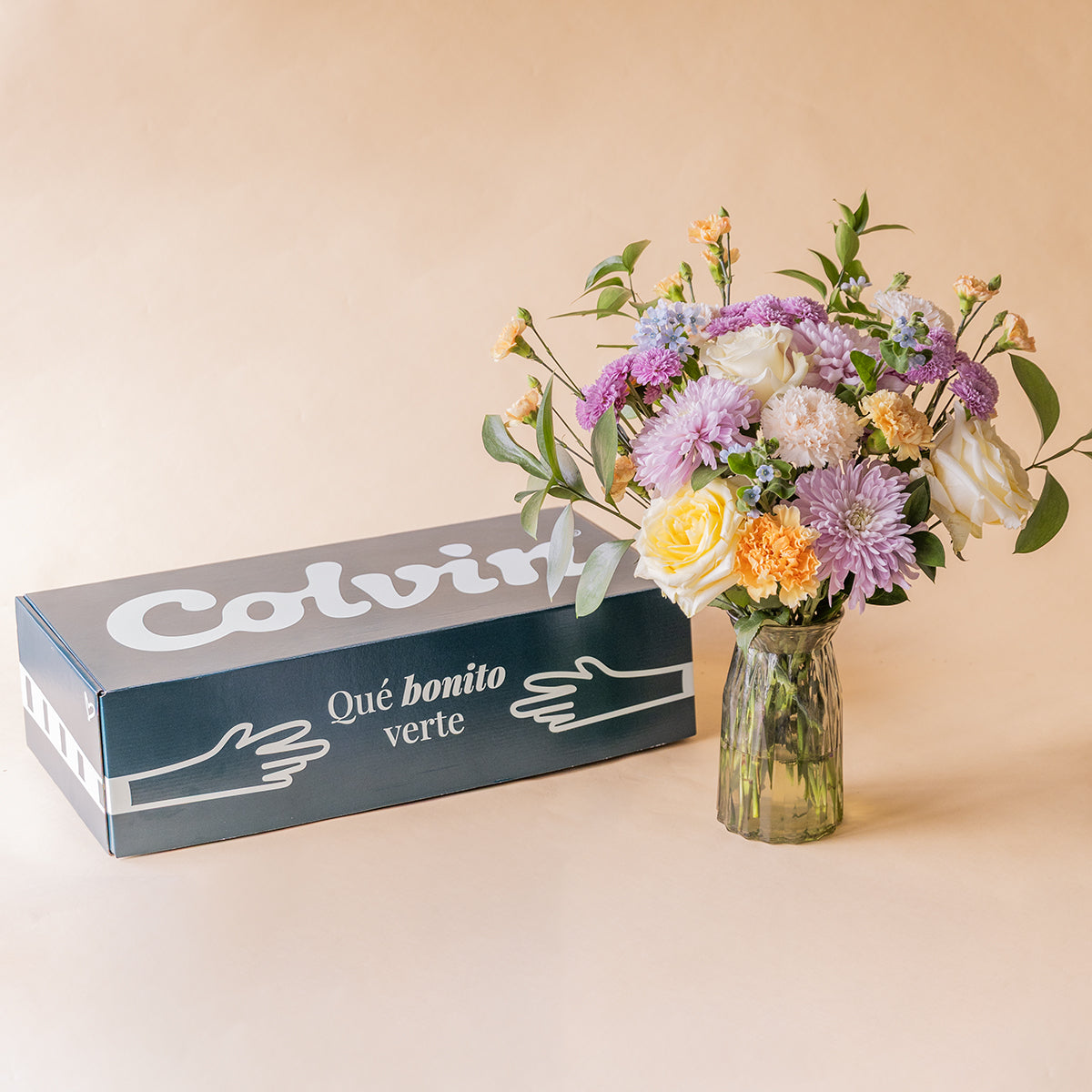Ramo de flores pastel de nacimiento de Colvin en jarrón de cristal junto a caja de envío "Qué bonito verte"