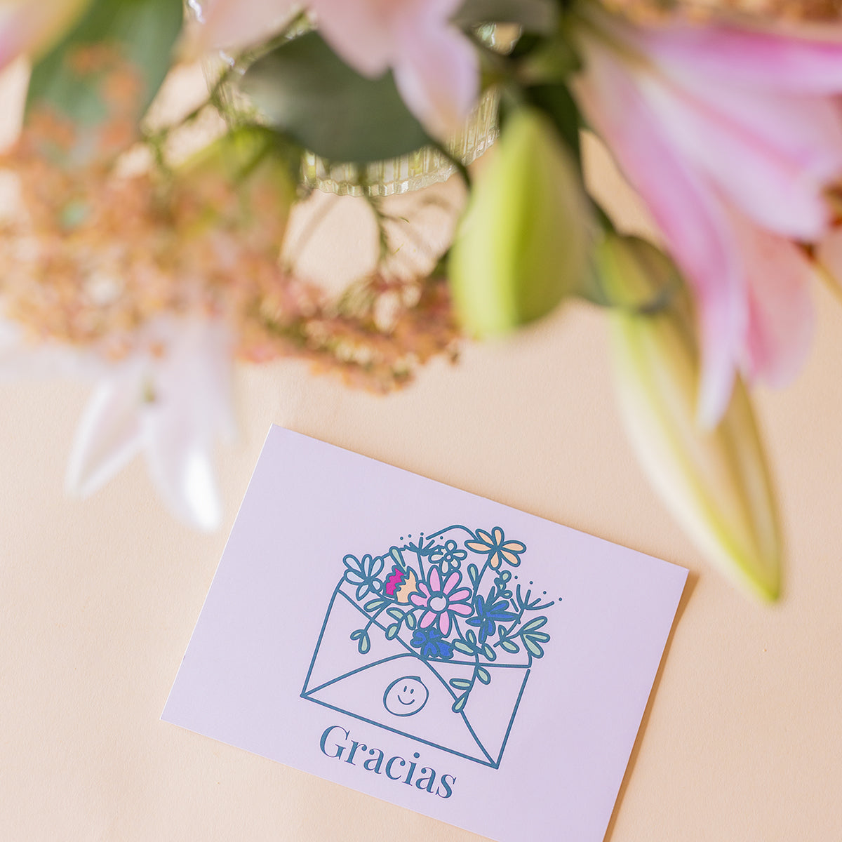 Detalle de tarjeta Gracias de Colvin junto a lirios rosas frescos