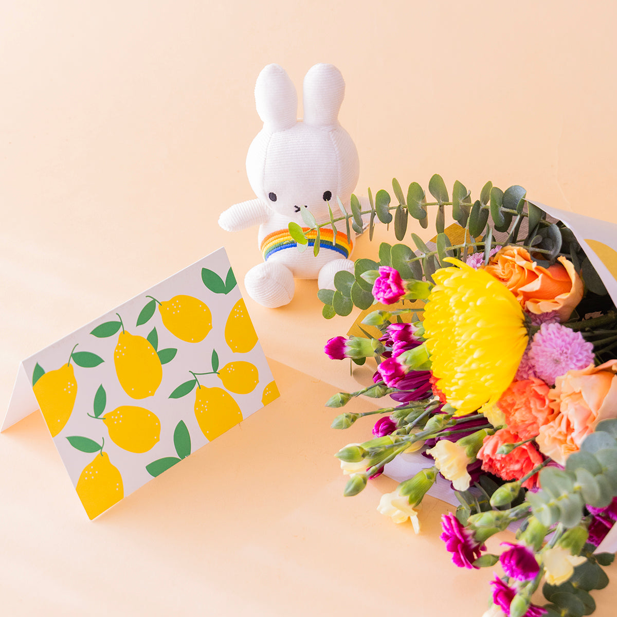 Ramo de flores coloridas con envoltorio, peluche y tarjeta