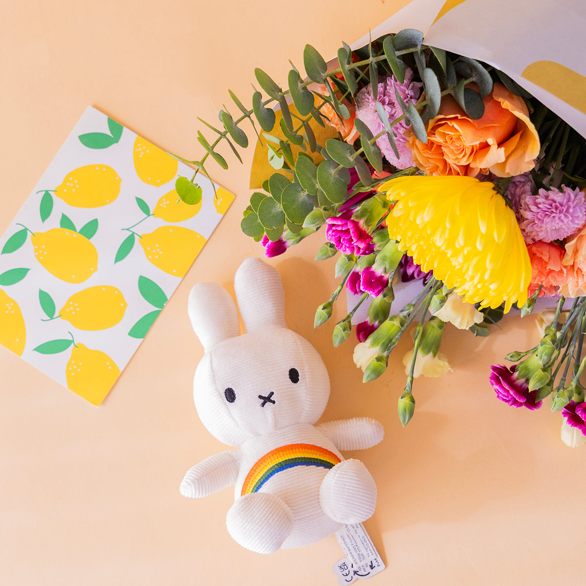 Ramo de flores coloridas con envoltorio, peluche y tarjeta