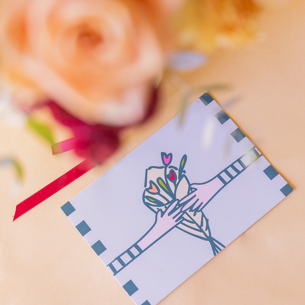 etalle macro de la tarjeta Más que Flores con el ramo desenfocado al fondo