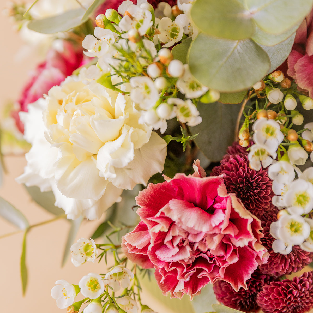 Detalle de clavel blanco, clavel rosa y crisantemo burdeos con flor de cera del arreglo La Bellota — Colvin