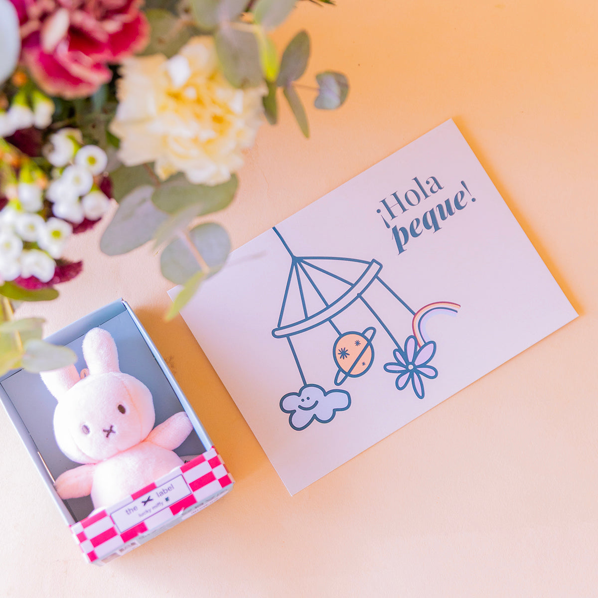 etalle cenital de Miffy rosa en caja y tarjeta "¡Hola peque!", arreglo al fondo