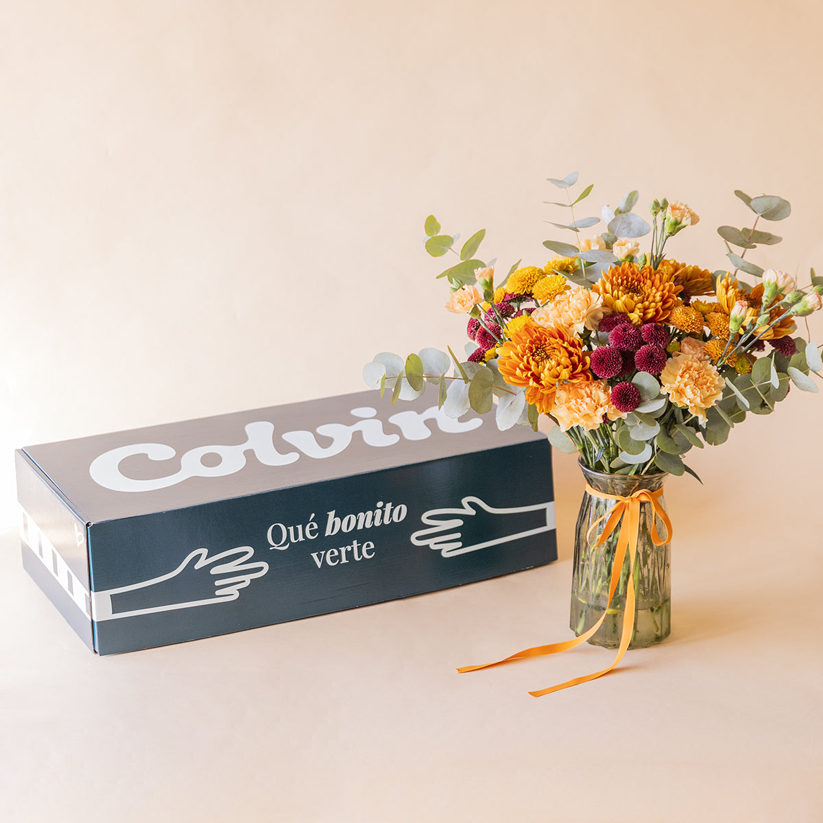 	Ramo La Calabaza en jarrón junto a caja de envío Colvin — flores naranjas a domicilio