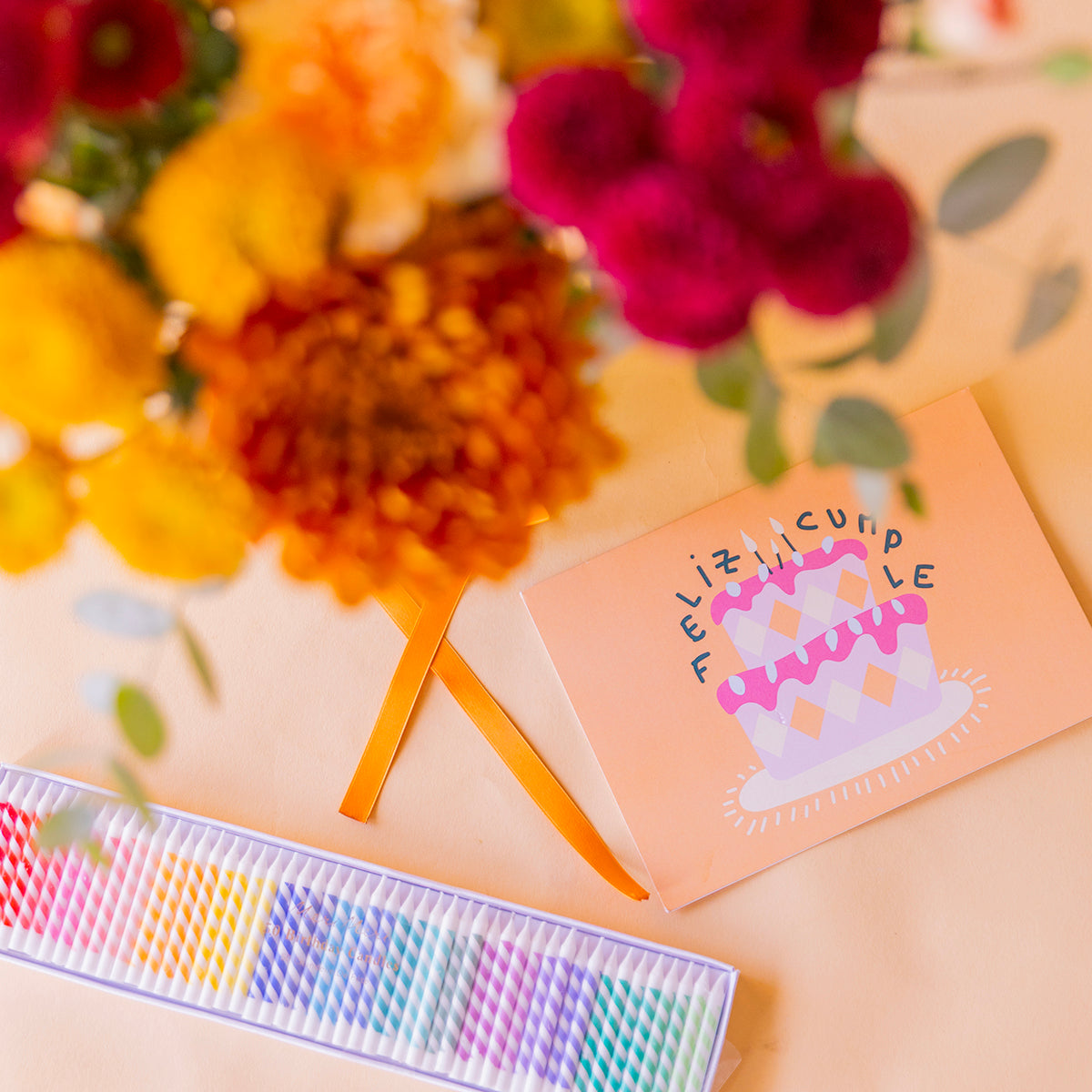 Detalle de tarjeta Feliz Cumple con ilustración de tarta y set de velas arcoíris junto al Ramo Calabaza — Colvin