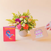 La Chispa - Arreglo floral de colores con libro horóscopo Escorpio y tarjeta Feliz Cumpleaños de Colvin.