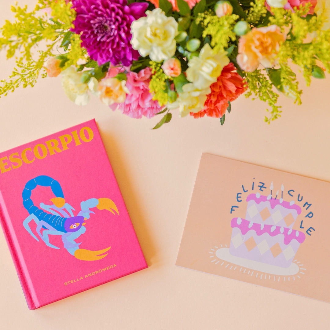 La Chispa - Libro horóscopo Escorpio y tarjeta Feliz Cumpleaños junto a arreglo floral de colores de Colvin.