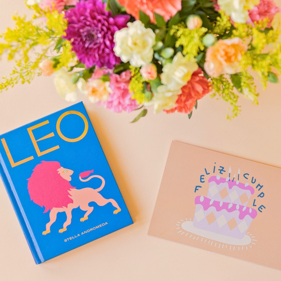 La Chispa - Libro horóscopo Leo y tarjeta Feliz Cumpleaños junto a arreglo floral de colores de Colvin.