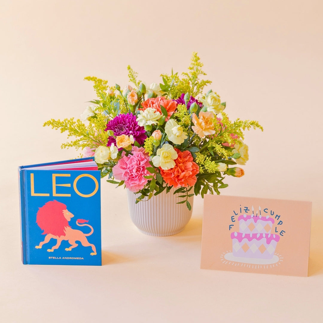 La Chispa - Arreglo floral con claveles, crisantemos y solidago junto a libro Leo y tarjeta de Colvin.