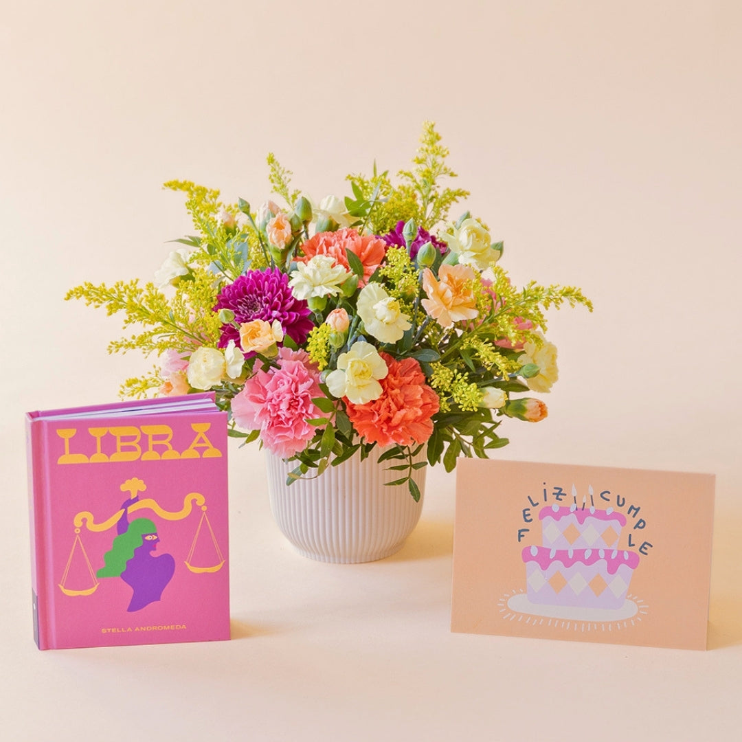 La Chispa - Arreglo floral con claveles, crisantemos y solidago junto a libro Libra y tarjeta de Colvin.