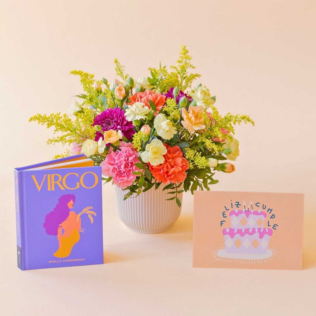 La Chispa - Arreglo floral con claveles, crisantemos y solidago junto a libro Virgo y tarjeta de Colvin.