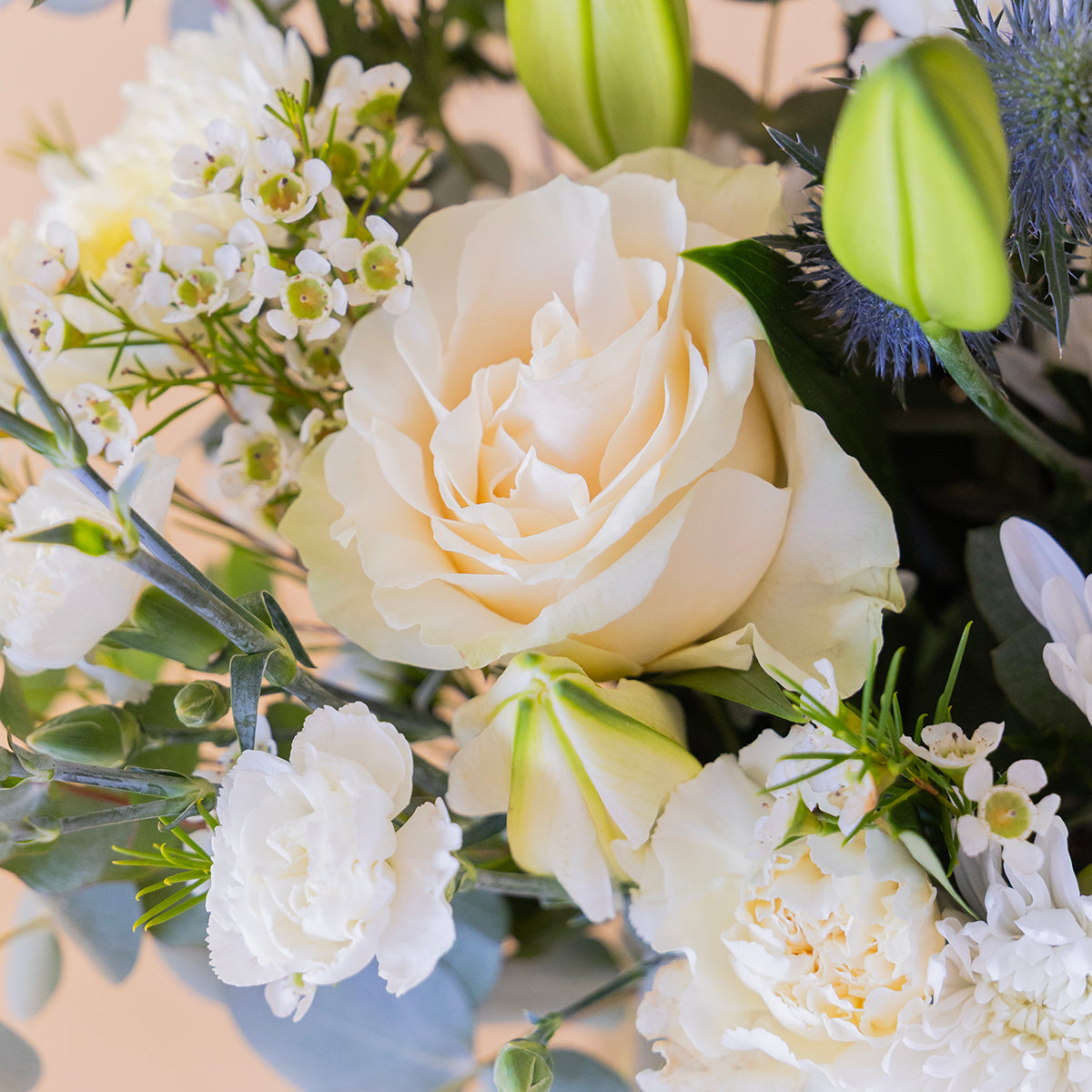 Ramo de flores blancas con lirios sobre fondo crema.