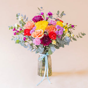 Ramo de flores coloridas sobre fondo crema.