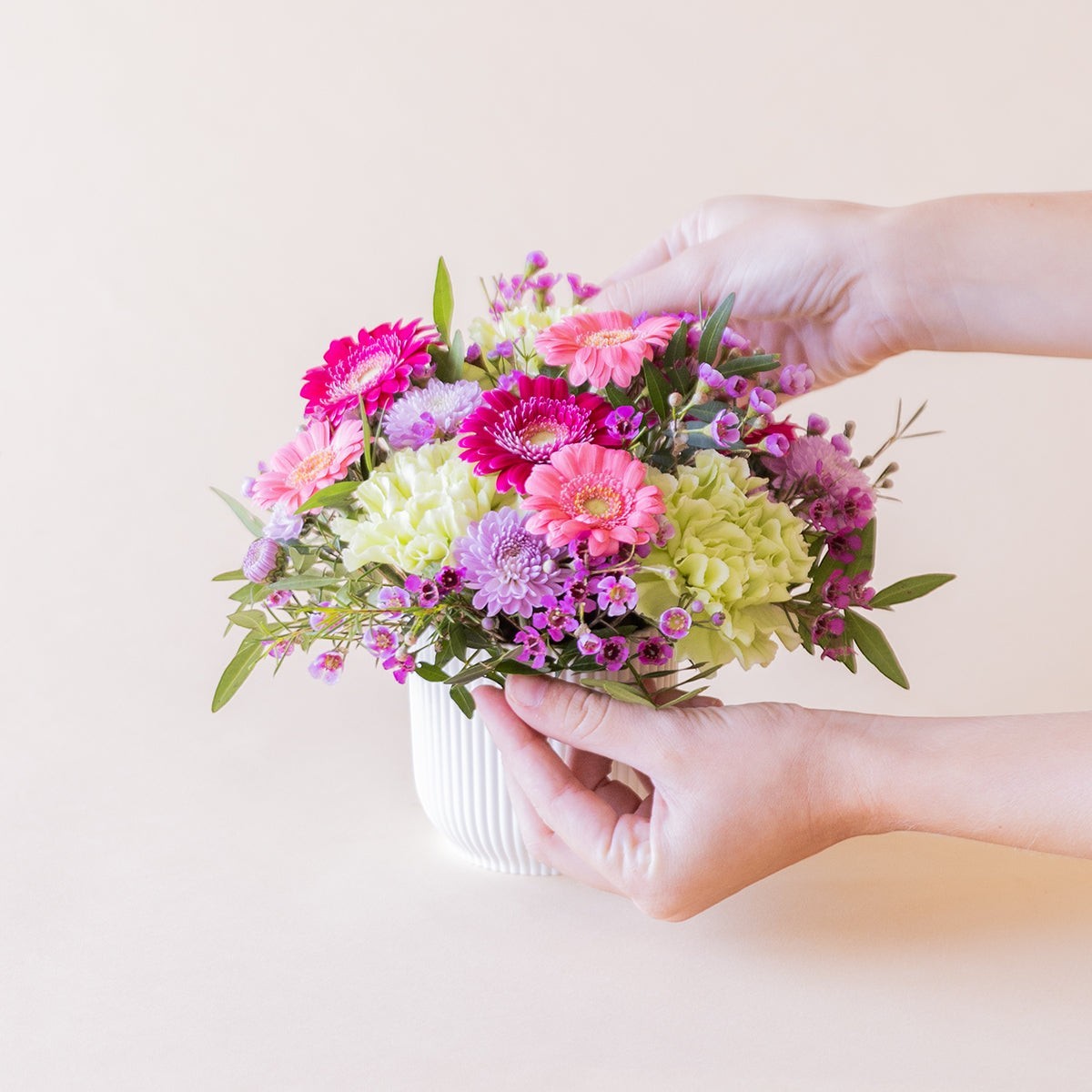 Arreglo floral mini Colvin con gerberas fucsia, claveles verdes y flores silvestres lila en maceta  reciclada