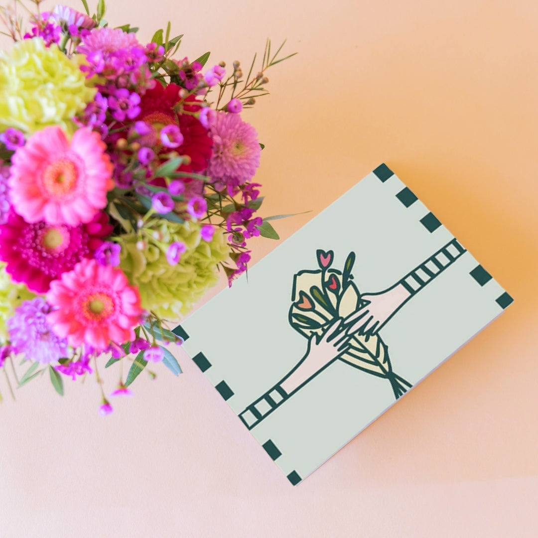 Detalle de tarjeta Colvin con ilustración de manos sosteniendo ramo de flores junto a arreglo floral colorido con gerberas y claveles