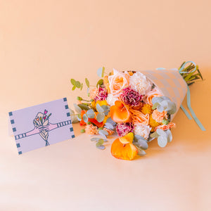 ramo Ginger tumbado en envoltorio cuadros blanco y azul con tarjeta Más que Flores, vista lateral